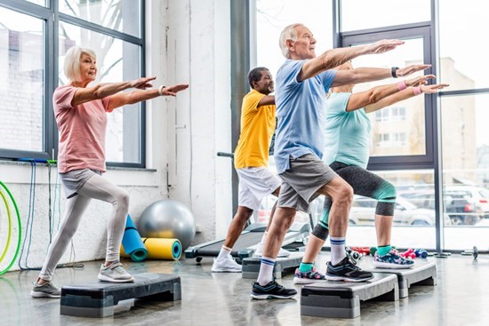 Senior fitness group spending onto platforms with arms outstretched forward