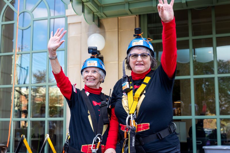 Tryon Estates residents Katherine Jeter and Lorraine DeCesare rappel building for cancer awareness.