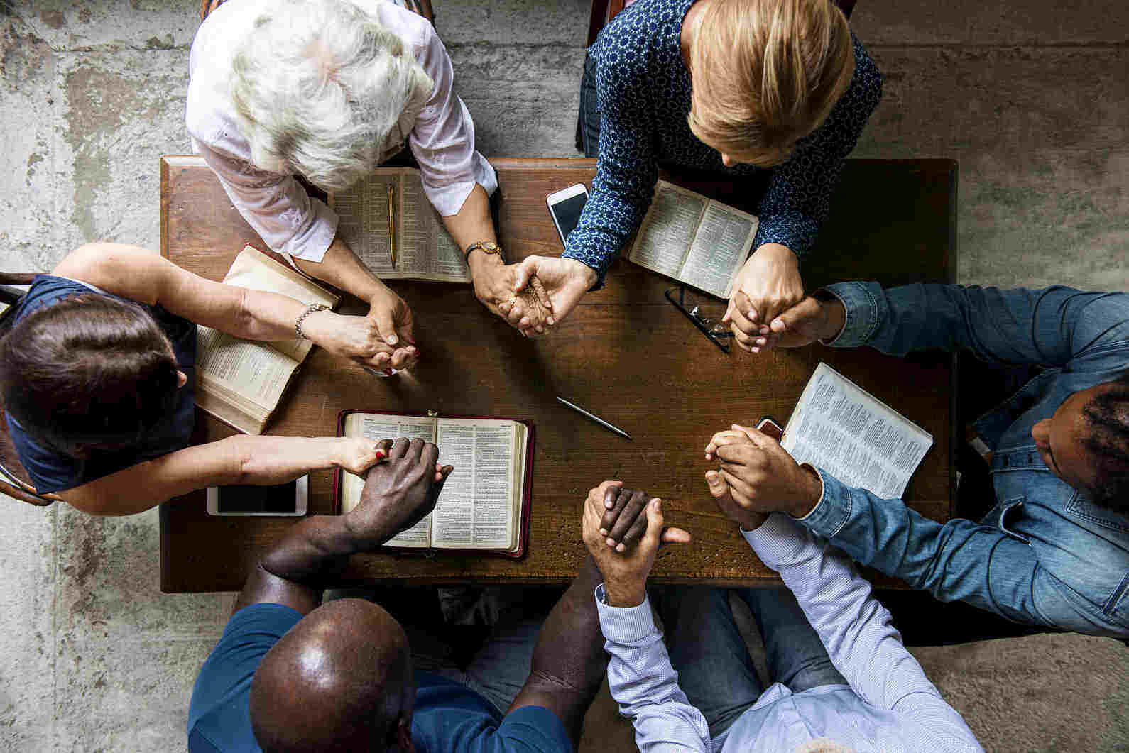 Prayer group, sitting together at a table holding hands