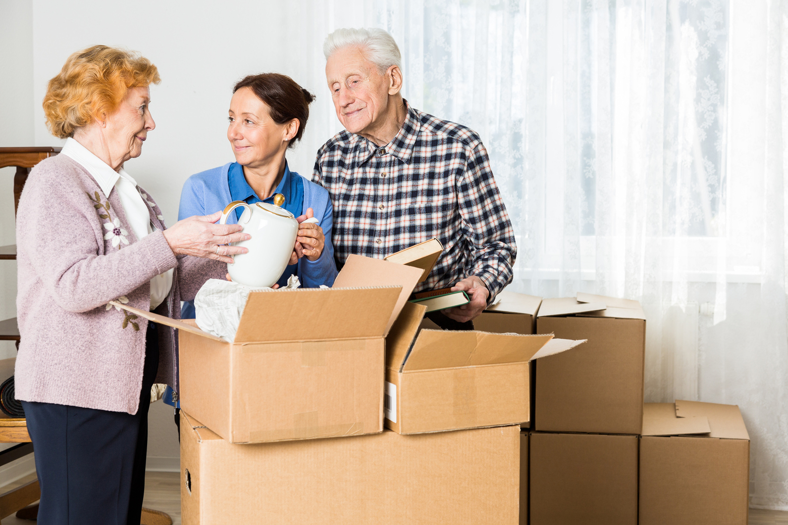 Three people looking at items as they downsize and move things into boxes