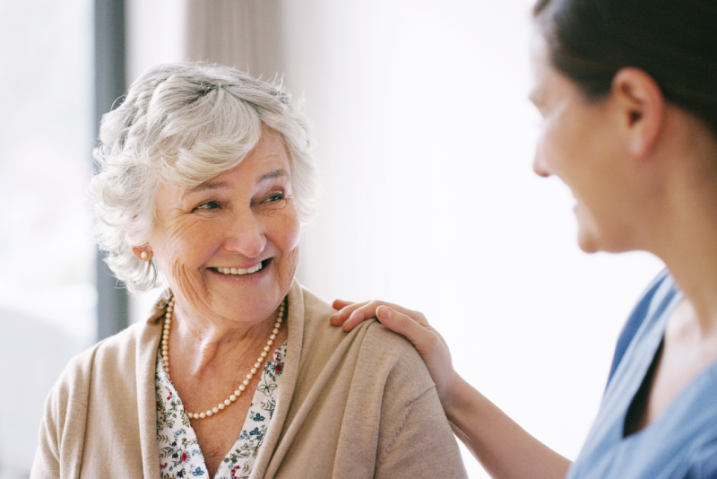 Healthcare worker putting her hand on elderly woman's should to consult her on medicare