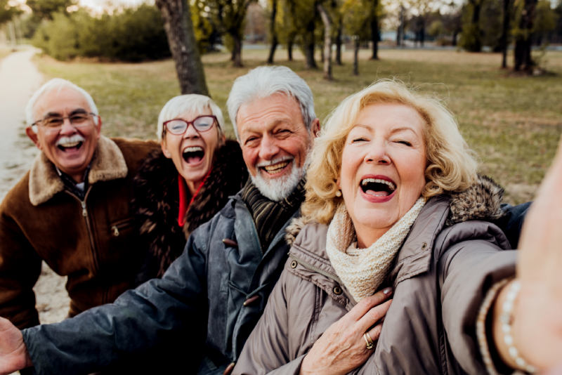 Group of senior friends posing for a selfie on a wooded trail at their retirement community