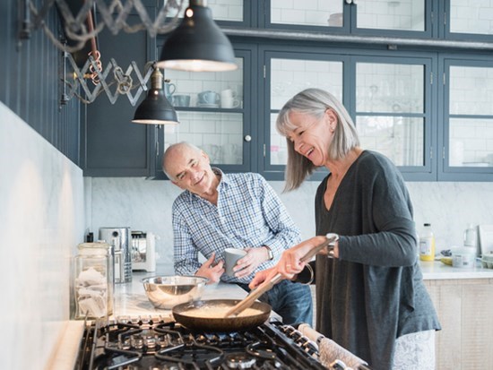 Happy senior couple cooking healthy food on stove