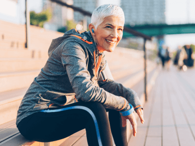 Senior woman runner taking a break sitting on a bench