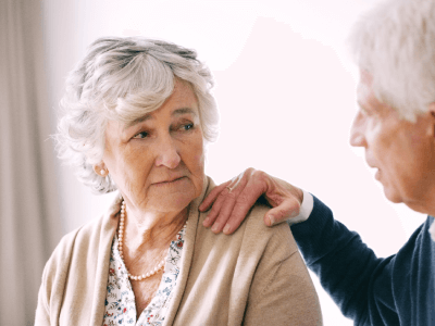 Senior man placing hand on shoulder of senior woman asking for forgiveness