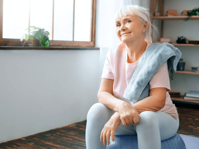 Senior woman sitting on an exercise ball after a home workout