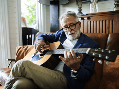 An elderly man is playing guitar