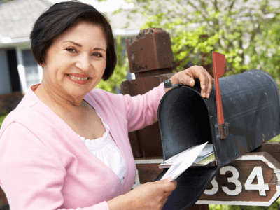 Smiling older Hispanic woman checking her mailbox