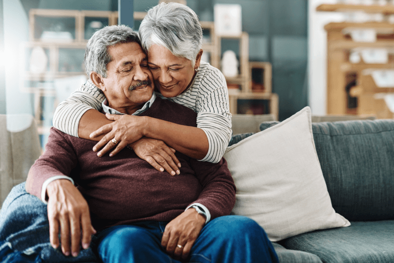 Cheerful elderly woman hugging her husband, and feeling financially secure at senior living community