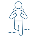 Simple line drawing of a person standing in water with their hands on their chest, shoulders slightly raised, and wavy lines indicating water around their legs.